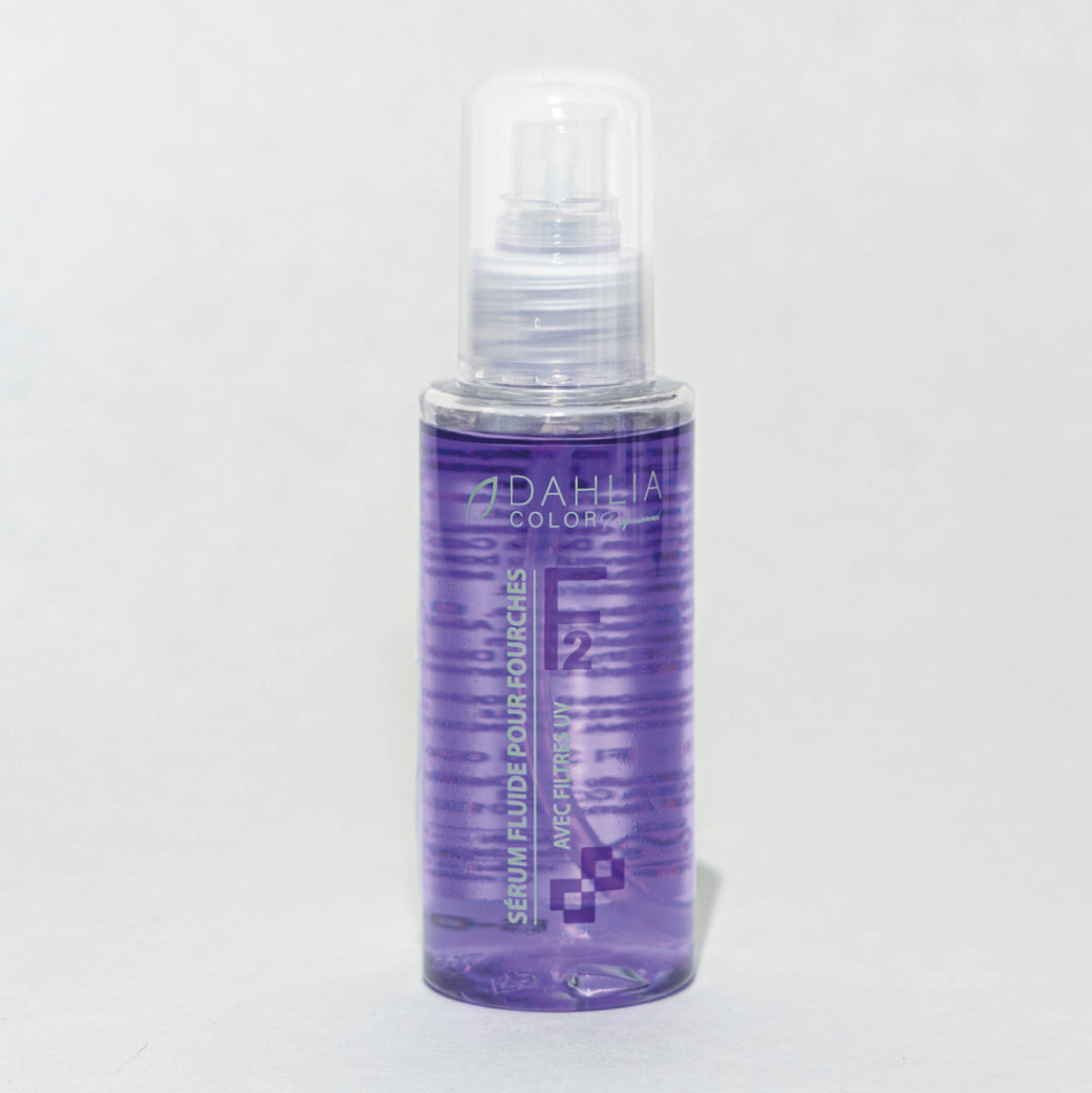 Un flacon transparent de Dahlia Color - Sérum Fluide aux Graines de Lin F2 avec un liquide violet et un bouchon pompe sur fond clair. Dahlia Color Professionnel
